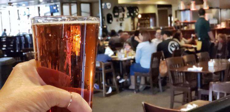 a person holds a pint of beer while looking across the brewery at Beaver Street Brewery in Flagstaff, AZ