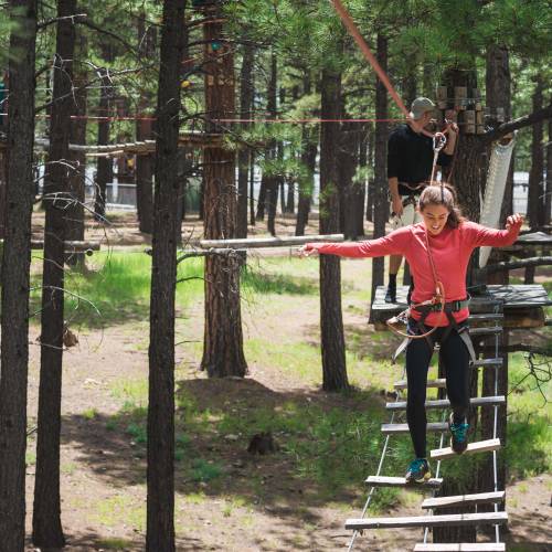 a woman having fun while walking on a rope course at Flagstaff Extreme Adventure Course