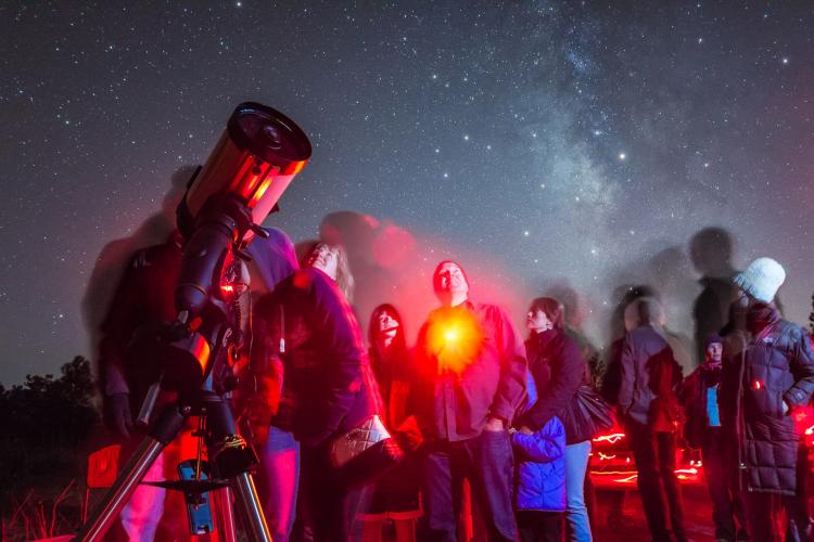 people admire the stars through a large telescope during Flagstaff Star Party