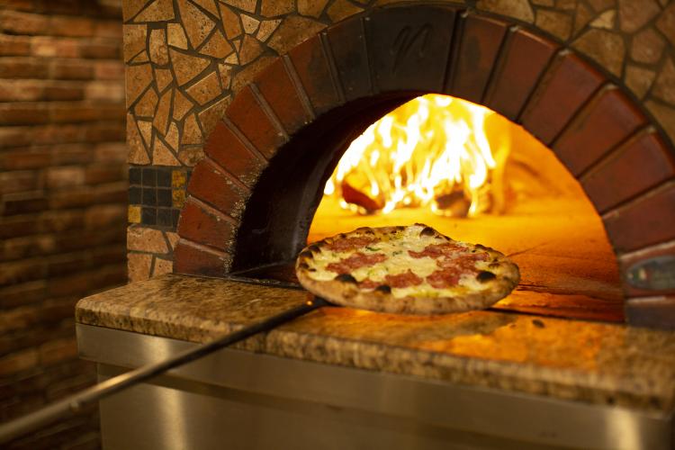 a pizza is put into a wood fire oven at Fat Olives in Flagstaff