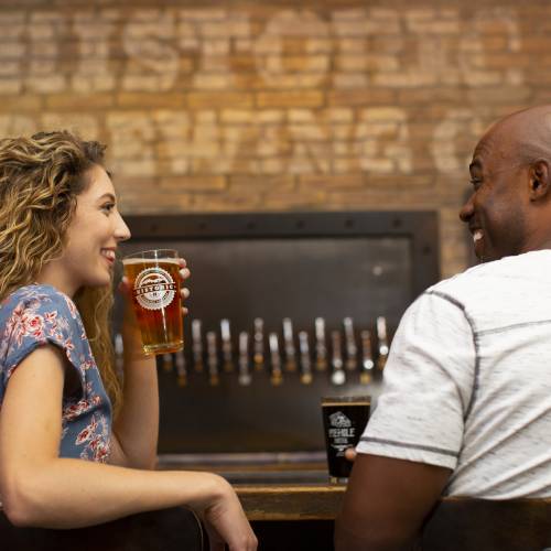 a man and woman enjoying pints of beer and good conversation at a Flagstaff, AZ brewery