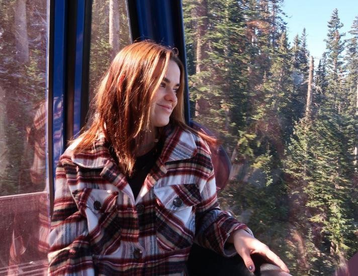 a woman wearing plaid looks out over the pine trees at Arizona Snowbowl in the fall