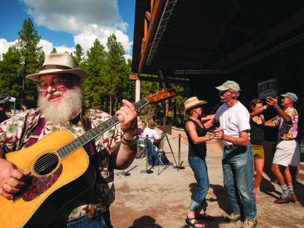 man plays guitar while couples dance behind him