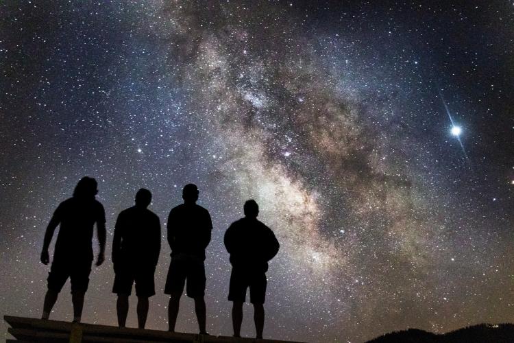 4 people looking up at the stars in the night sky