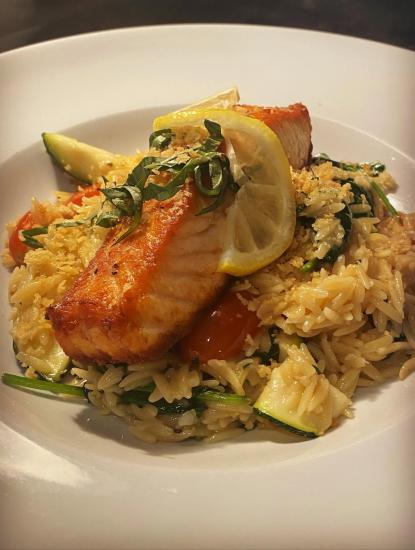 A piece of salmon with lemon and orzo from 1899 Bar & Grill
