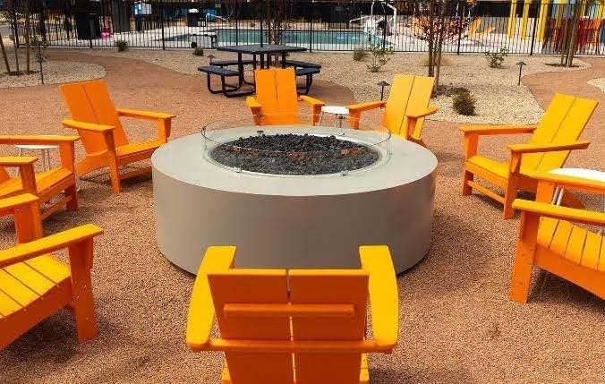 Yellow patio chairs surround a firepit in an outdoor area at Americana Motor Hotel.