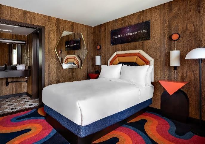 A hotel room at Americana Motor Hotel with retro-inspired decor and wooden paneling.