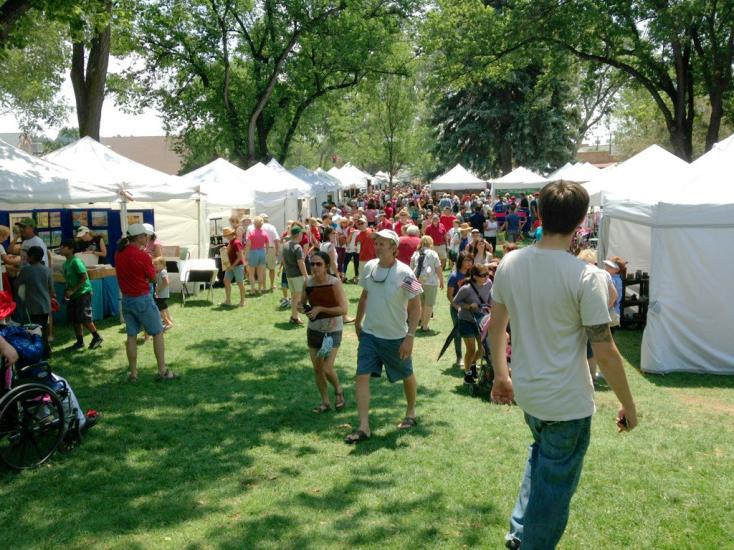 A crowd of people walk around local vendors during Art In The Park.