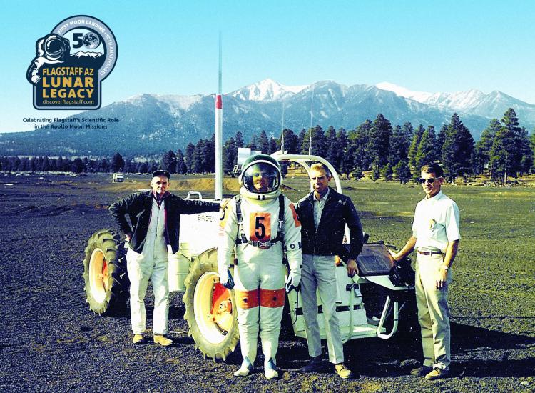 A 1969 photo of four men, including one in an astronaut suit, from the stand with lunar rover vehicle simulator "Explorer"