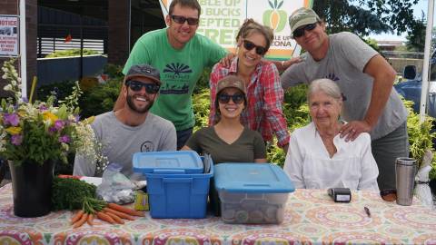 People gather behind a vendor table at Flagstaff Community Market