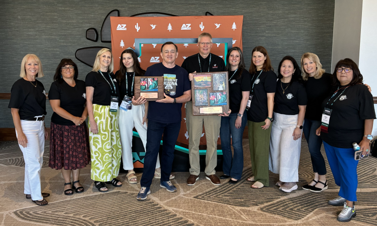 The Discover Flagstaff team and partners standing in front of a large AZ state cutout while holding an award.