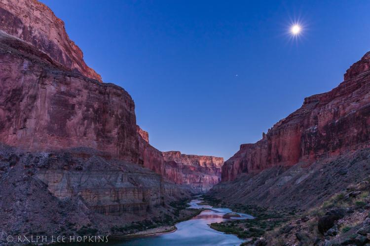 waterway splitting through the Grand Canyon with the sun and canyon walls reflecting in the water