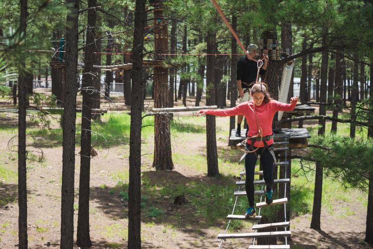 a woman having fun while walking on a rope course at Flagstaff Extreme Adventure Course