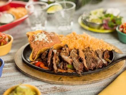 A plate of fajitas surrounded by colorful ceramic bowls