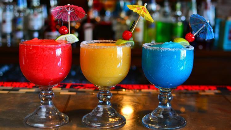 Three brightly colored margaritas in red, yellow, and blue