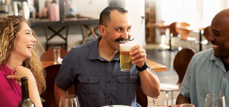 man drinking beer while laughing with friends