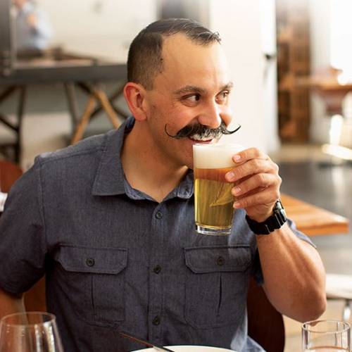 man drinking beer while laughing with friends