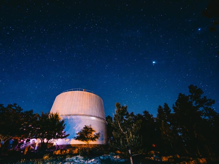 White exterior of Lowell Observatory at night. The sky is full of stars