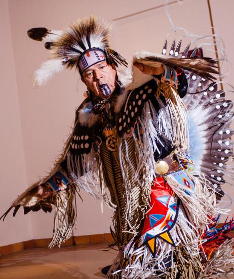 A man in a traditional Native American wardrobe with white feathers at the Museum of Northern Arizona Zuni Festival.