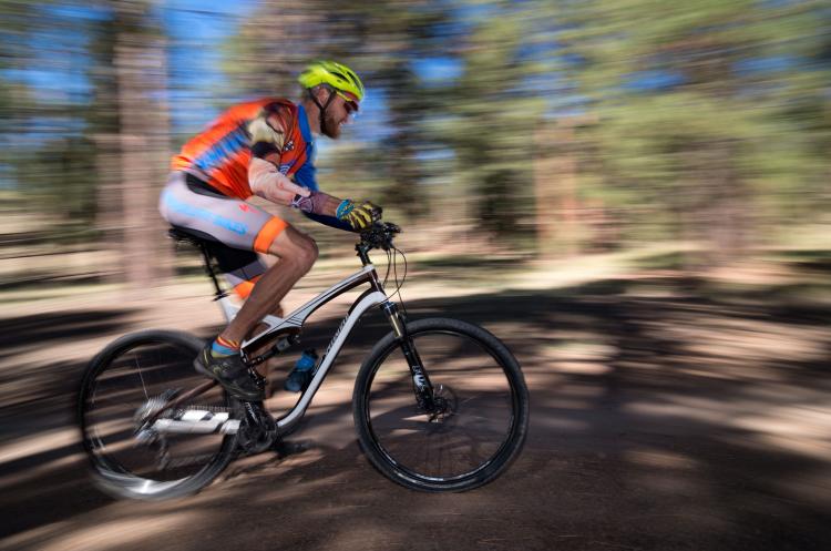 A man mountain bikes through the woods in Flagstaff. The biker is in focus while the rest of the image is motion blurred