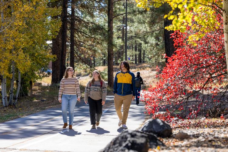 3 NAU students walking on campus on a colorful fall day.