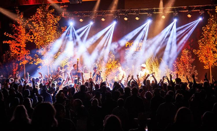 A band plays on stage at night during the Pickin in the Pines festival