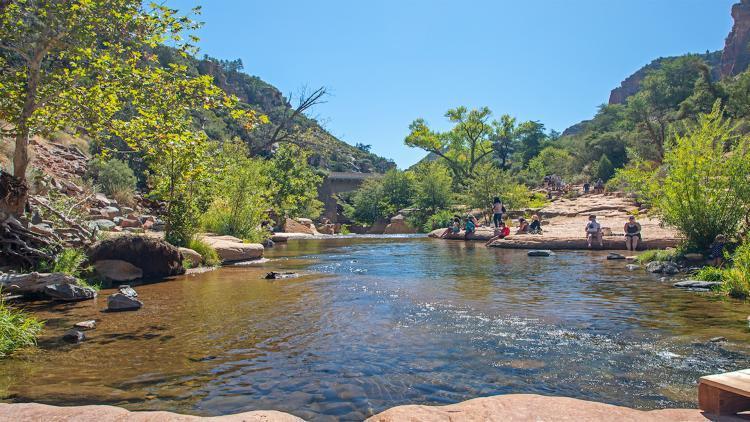 People lounge by the bumbling waters of Slide Rock State Park. 