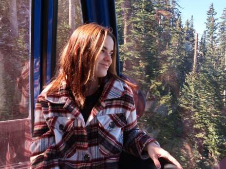 a woman wearing plaid looks out over the pine trees at Arizona Snowbowl in the fall