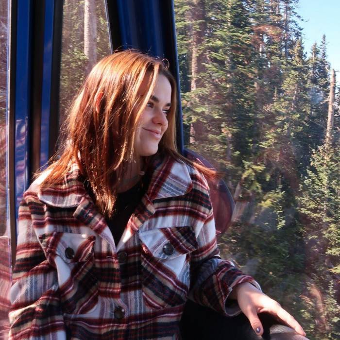a woman wearing plaid looks out over the pine trees at Arizona Snowbowl in the fall