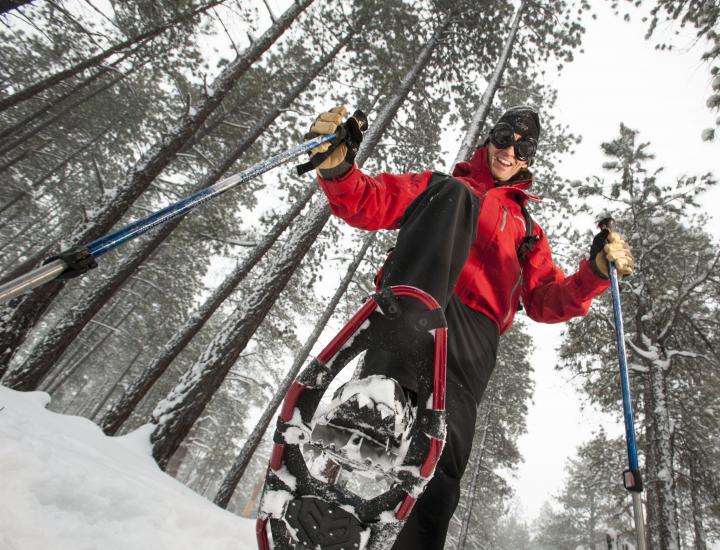 a person lifts their snowshoe over the camera while snowshoeing in Flagstaff