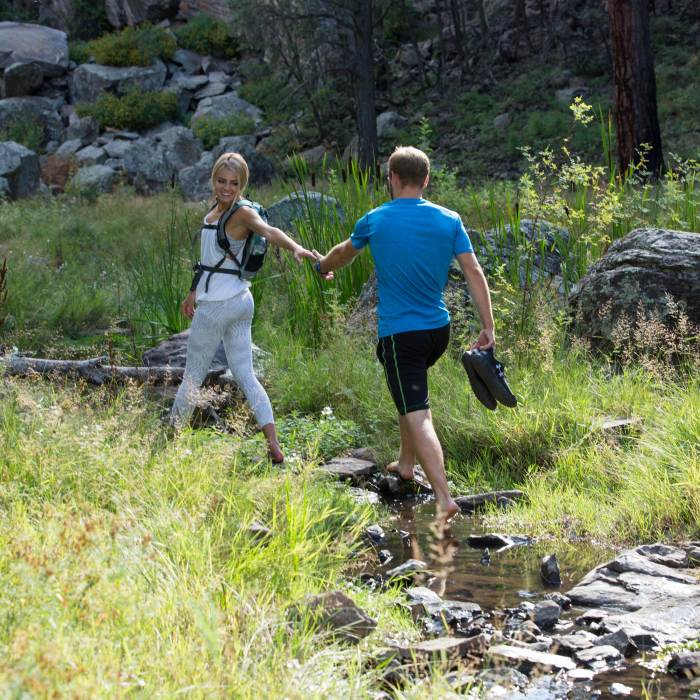 Couple holds hands while hiking along a trail in the woods in Flagstaff