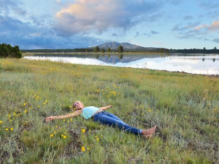 woman lying in the grass near a lake