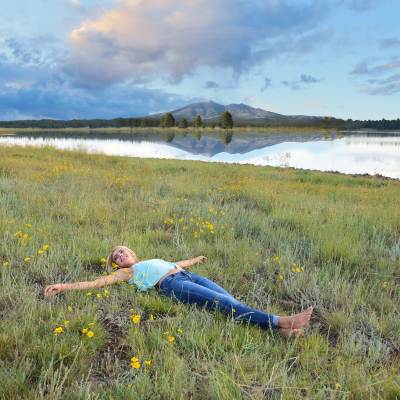 woman lying in the grass near a lake
