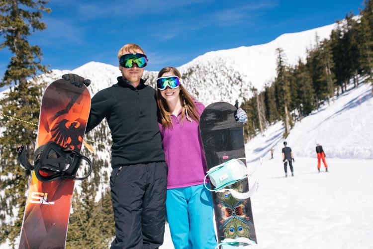 two snowboarders posing on side of mountain slope