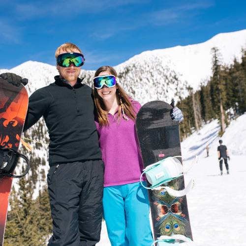 two snowboarders posing on side of mountain slope