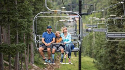 family riding scenic chairlift up mountainside