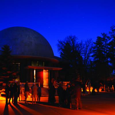 People stand outside lowell observatory at night