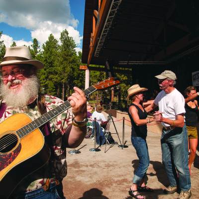 man plays guitar while couples dance behind him
