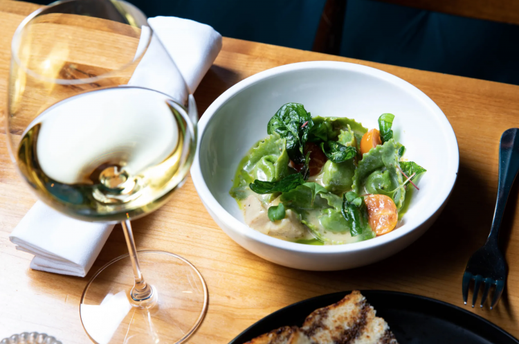 white wine and a bowl of veggies on a table