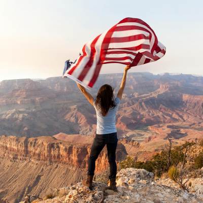 a woman holding a flag while overlooking the Grand Canyon near Flagstaff