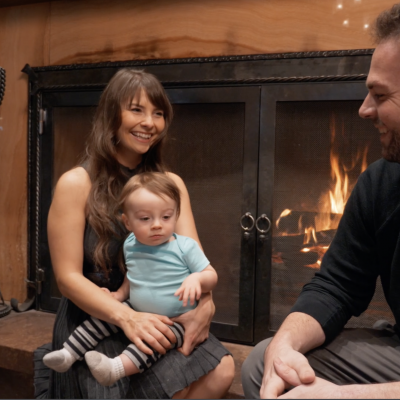 Family with small child sitting together near a fireplace in a Flagstaff AZ hotel