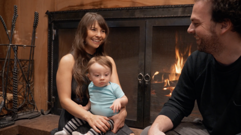 Family with small child sitting together near a fireplace in a Flagstaff AZ hotel