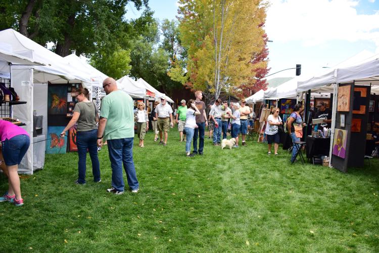people admire artworks at Art In The Park on the grass in downtown Flagstaff
