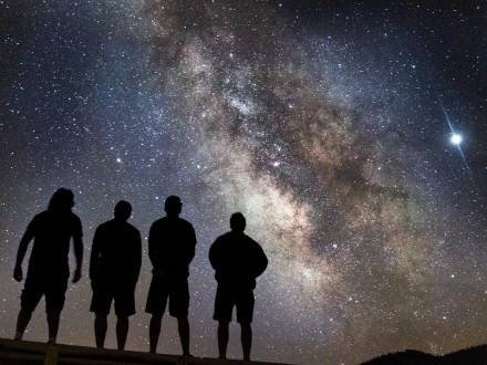 4 people looking up at the stars in the night sky