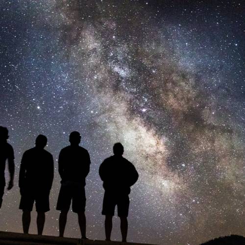 4 people looking up at the stars in the night sky