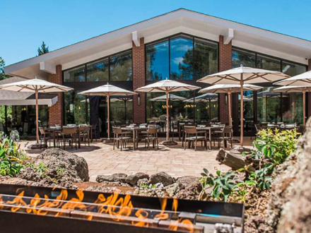 Outdoor patio at Little America Hotel on a sunny day. There are many tables with umbrellas and an outdoor fire