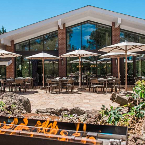 Outdoor patio at Little America Hotel on a sunny day. There are many tables with umbrellas and an outdoor fire
