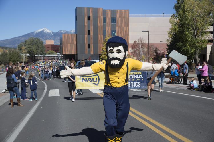 the Northern Arizona University Lumberjack mascot parades down a street in Flagstaff during the NAU homecoming event