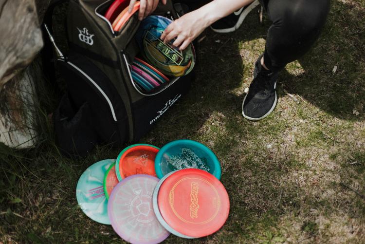 A bag filled with frisbees is looked through by someone outside. 