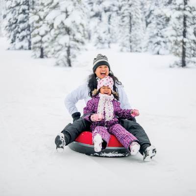 A mother and her child rides a sled in the snow in Flagstaff, AZ.